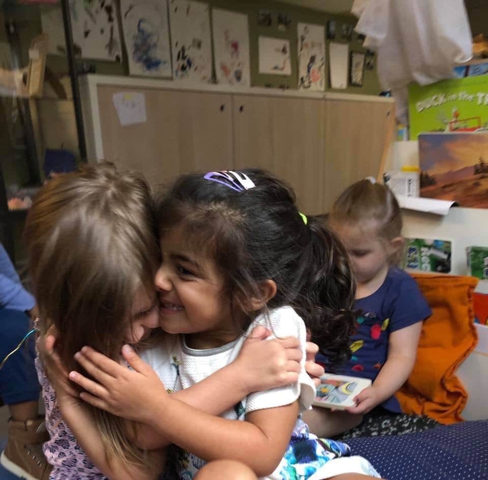 two girls hugging after watching a being and belonging slideshow