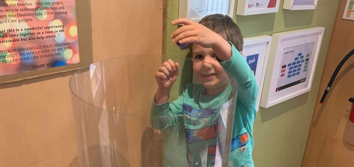 child dropping plastic lids into collection bin