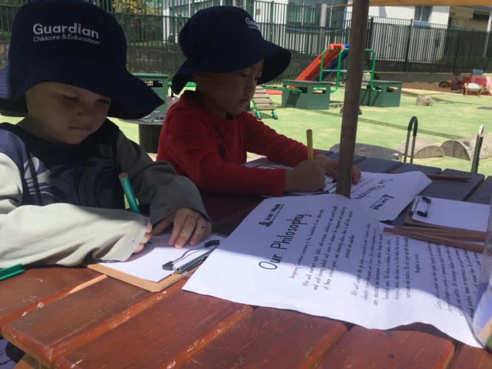 children sitting outside in shade reviewing centre philosophy