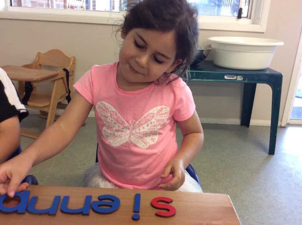 child using letter blocks to spell her name, learning about literacy