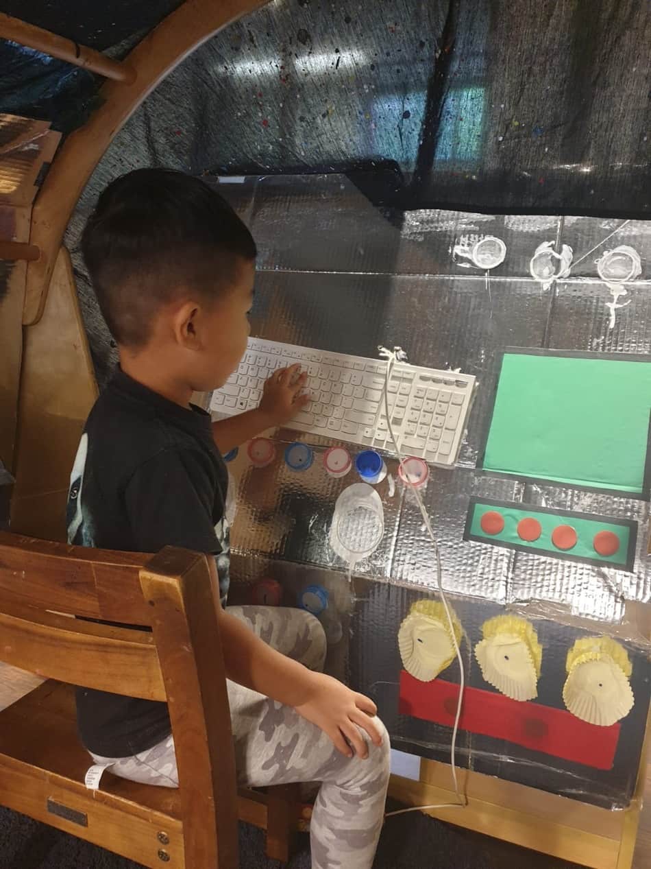 child pressing buttons on control unit in space station