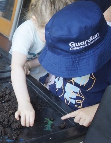 child looking at worms in dirt