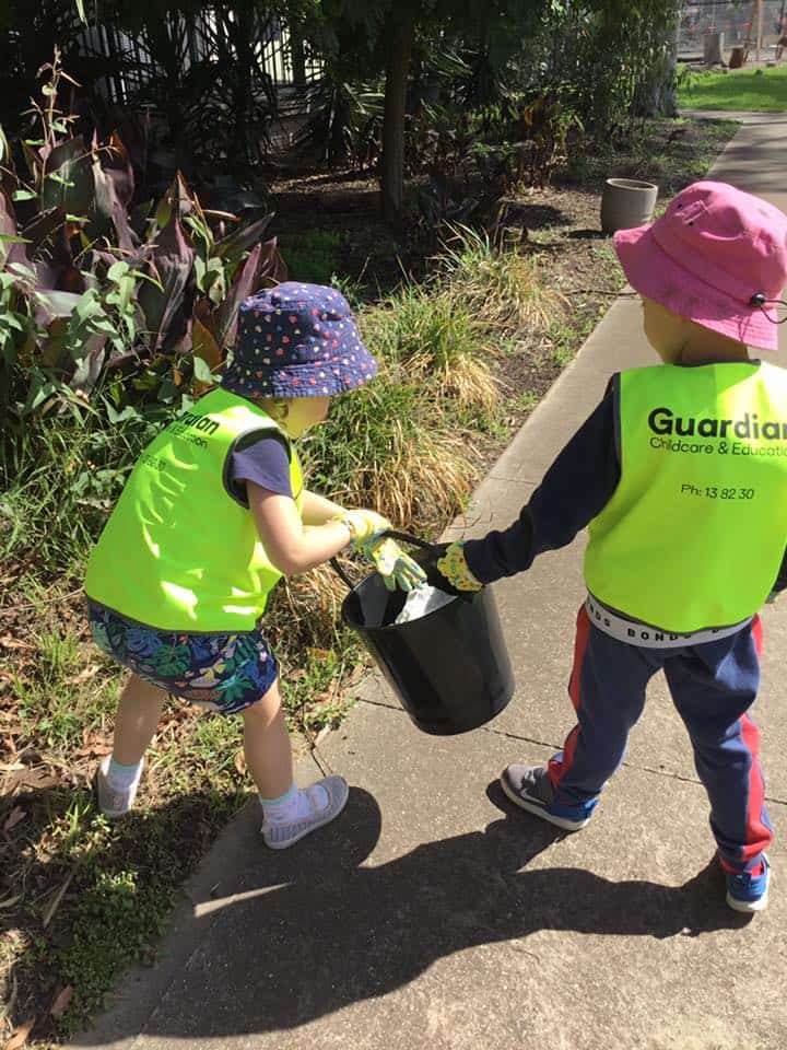 Children at Altona North wearing safety vests and holding bucket of rubbish