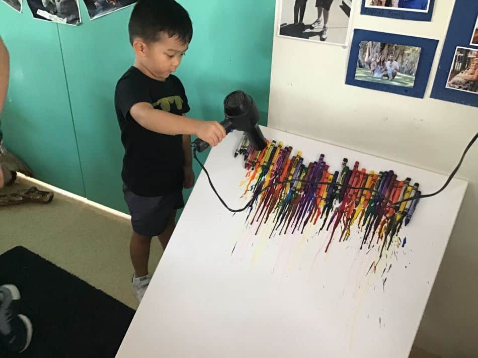 child using hairdryer and participating in crayon melting experiment