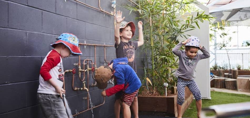 children wearing hats and laughing outdoors, showing their clean hands after using hand sanitiser