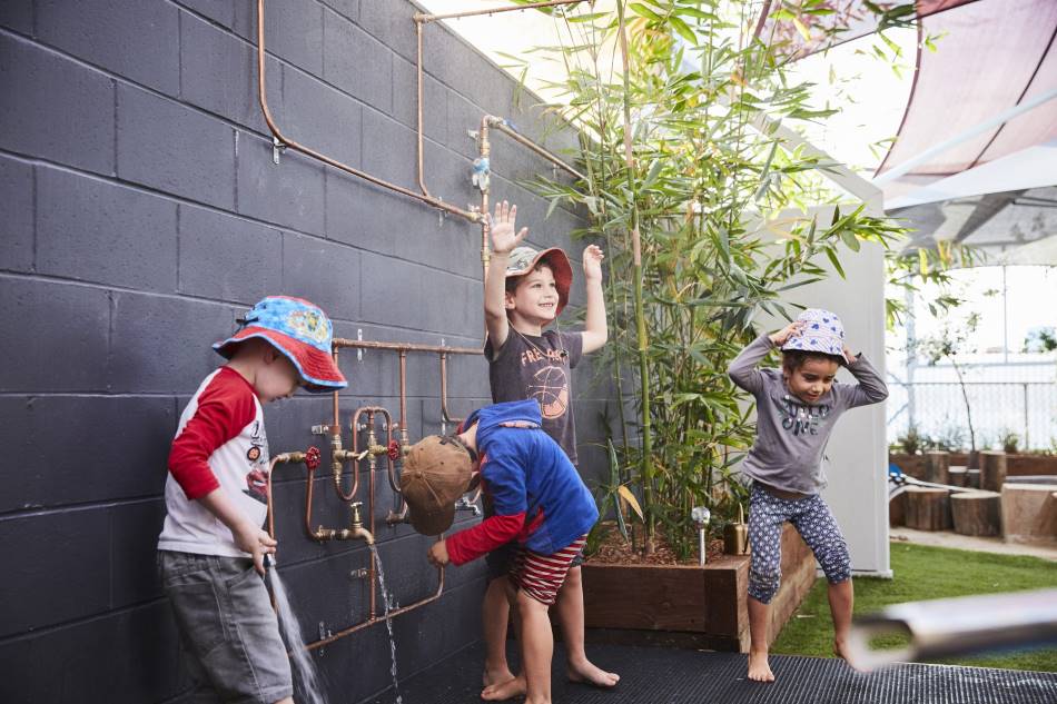 children wearing hats and laughing outdoors, showing their clean hands after using hand sanitiser