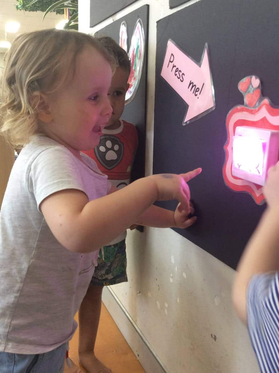 child smiling and ready to press magic hug button