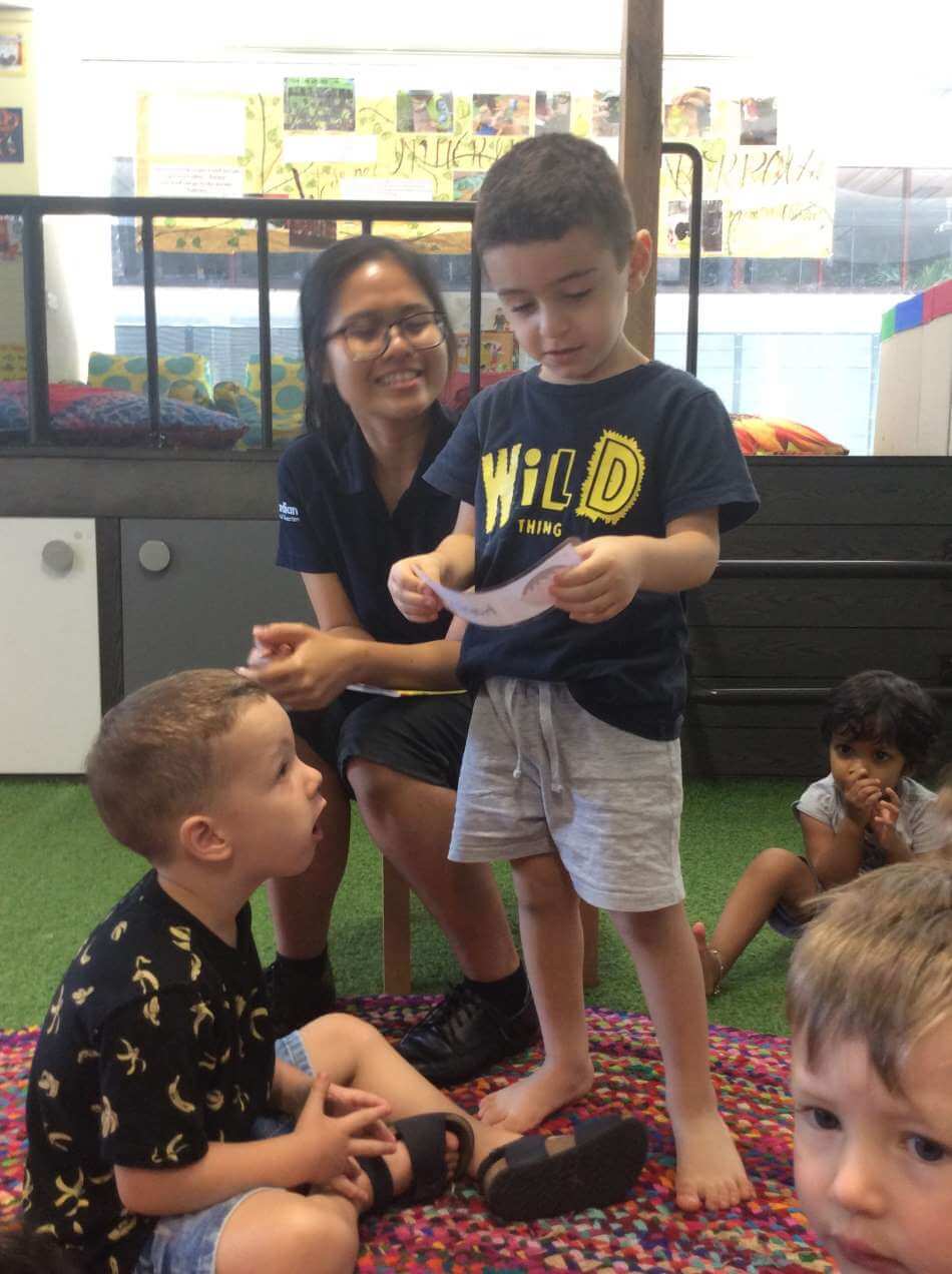 child standing in front of peers and using emotion cards