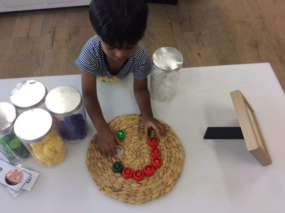 child using bottle caps on emotion cards table