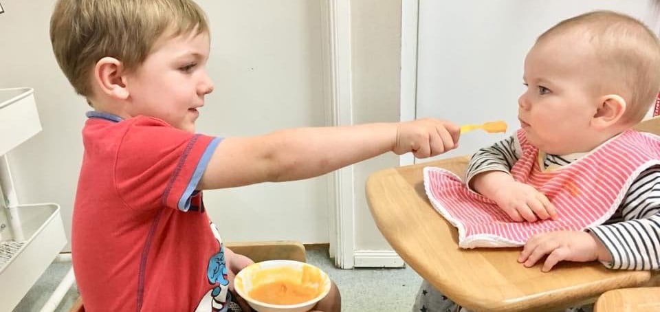 child feeding baby in highchair as part of leadership program