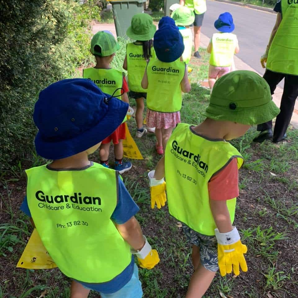 Children from Guardian Acacia Gardens wearing gloves, hats and safety vests while collecting rubbish for Clean Up Australia Day