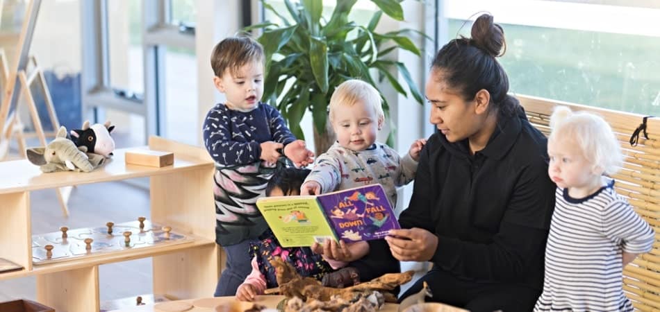 Children reading book with educator