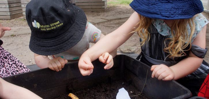 children exploring their curiosity with worm farm