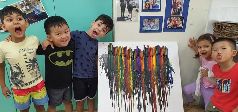 children laughing and standing next to their completed crayon melting experiment at Guardian Tempe