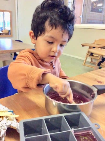 child stirring melted candle wax for Earth Hour activity