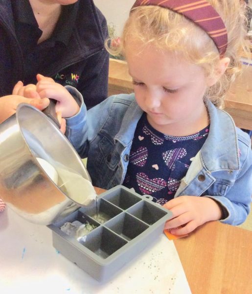 child pouring candle wax into moulds for Earth Hour learning experience