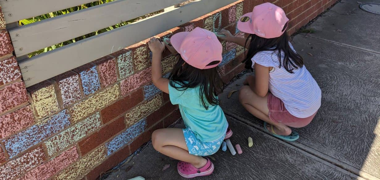 Children colouring fence as part of backyard kinder program