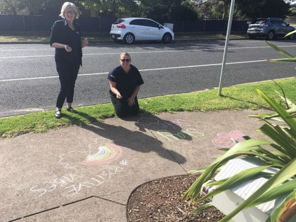 Educators with rainbow chalk mural on footpath