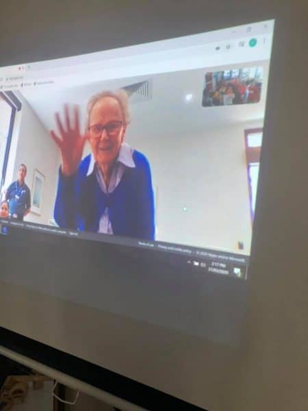aged care resident waving at children on Zoom