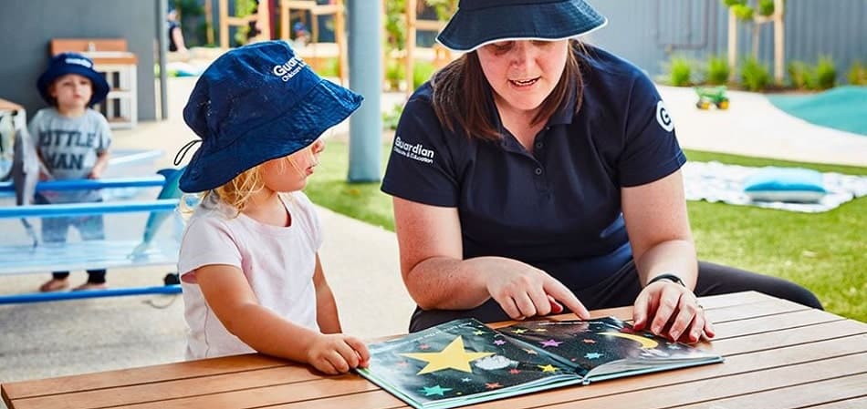 Educator reading a book to child outside