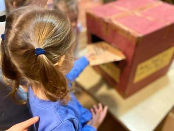 child putting letter to her pen pal into mailbox