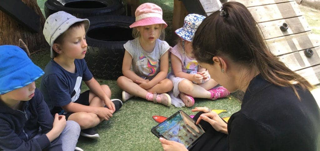 children sitting with Educator learning Spanish through ELLA program