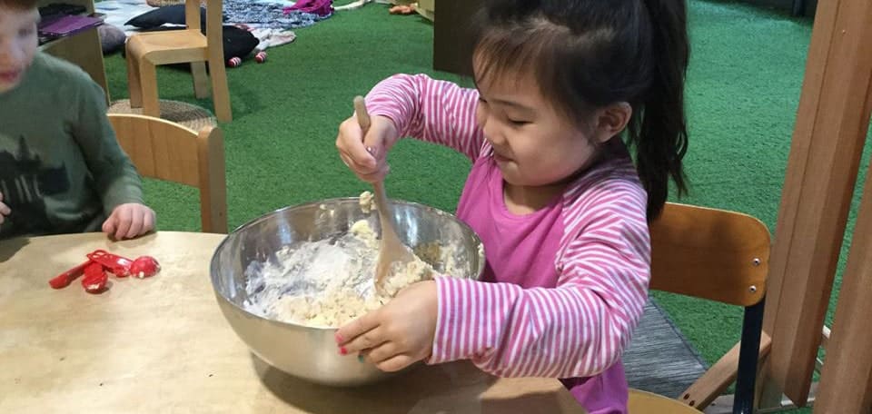 child at Guardian Blight St stirring hot crossed bun dough during weekly cooking experiences