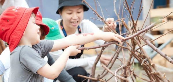 Educator interacting with children and sticks at Brunswick