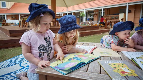 Children reading books outside at Balmain Cove