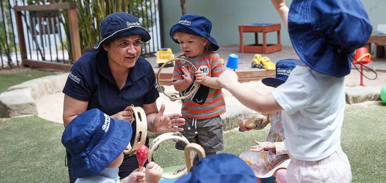 Children playing with music instruments and educator at Lilyfield