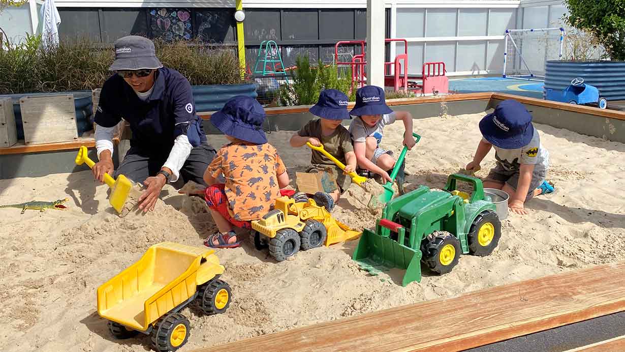 Children playing in sandpit with educator