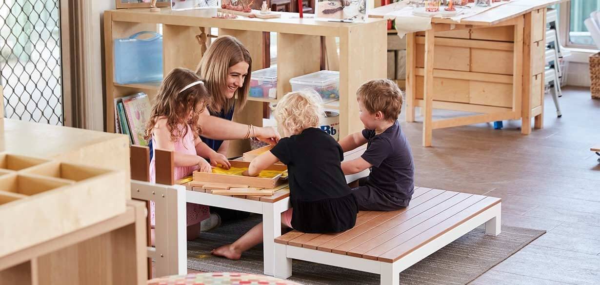 Educator sitting with children indoors at Paradise