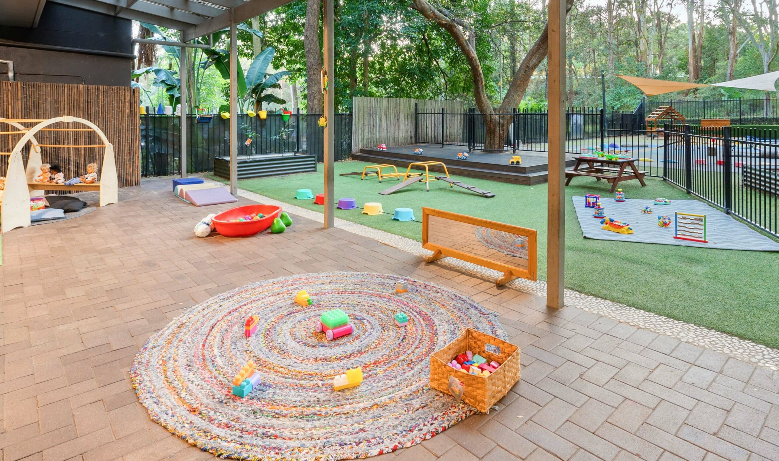 Spacious and engaging outdoor play area at Guardian Childcare Macquarie Park, NSW, featuring climbing frame, slide, play equipment and natural shade sails.