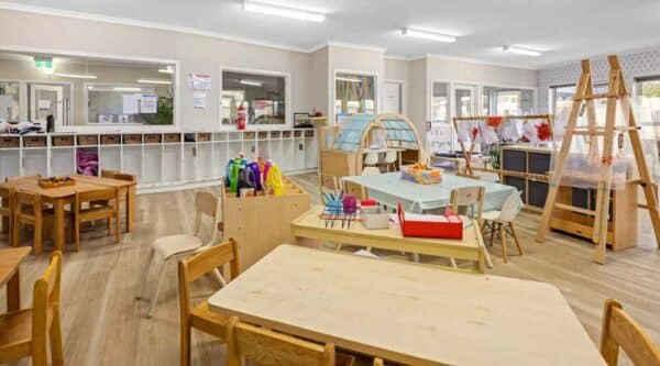 Bright and spacious classroom at Guardian Childcare Sydenham VIC, featuring wooden tables and chairs, organised learning stations, and natural light, creating a welcoming early learning environment.