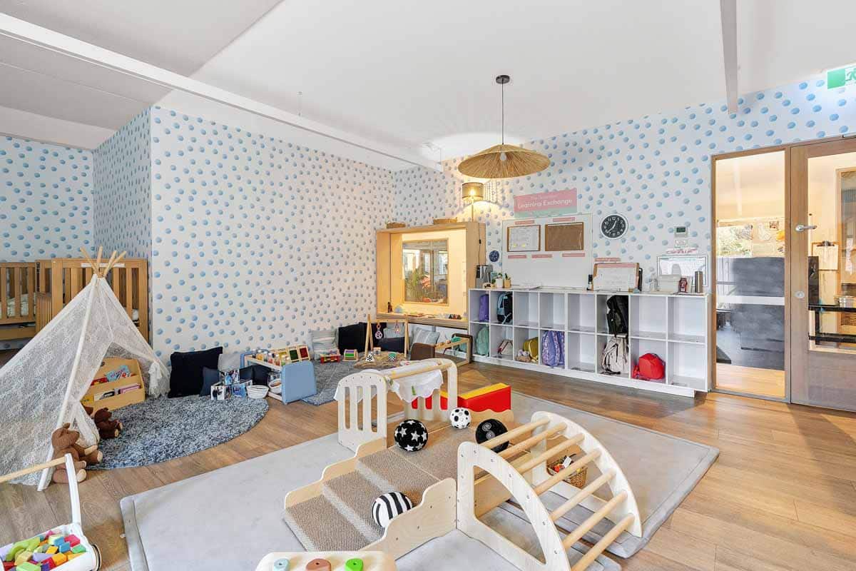 Cosy play area at Guardian Childcare McKinnon nursery, featuring teepee reading nook, soft toys, and age-appropriate wooden climbing frame.
