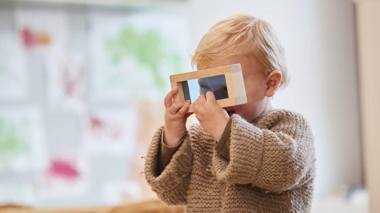 Toddler exploring wooden mirror sensory play early learning