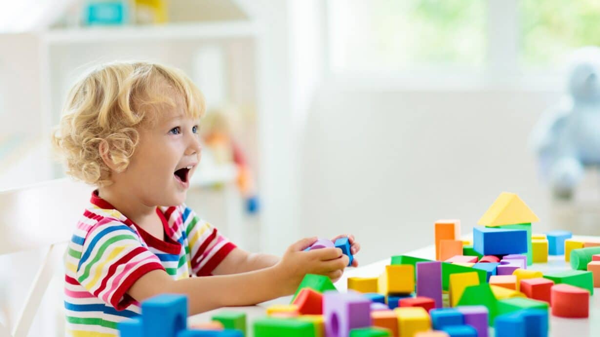 Toddler playing with colourful building blocks at childcare